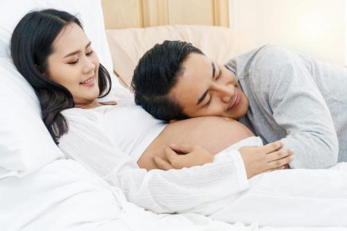 Husband lying and listening the belly of pregnant wife