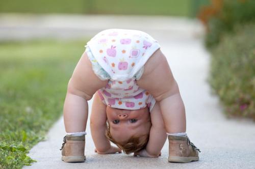 One year baby girl playing upside down on the street